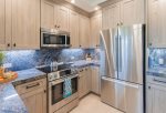 Kitchen features custom driftwood cabinets, granite countertops, stove, a convection oven with a warming drawer, freezer/refrigerator, microwave, dishwasher, and a sink with disposal
